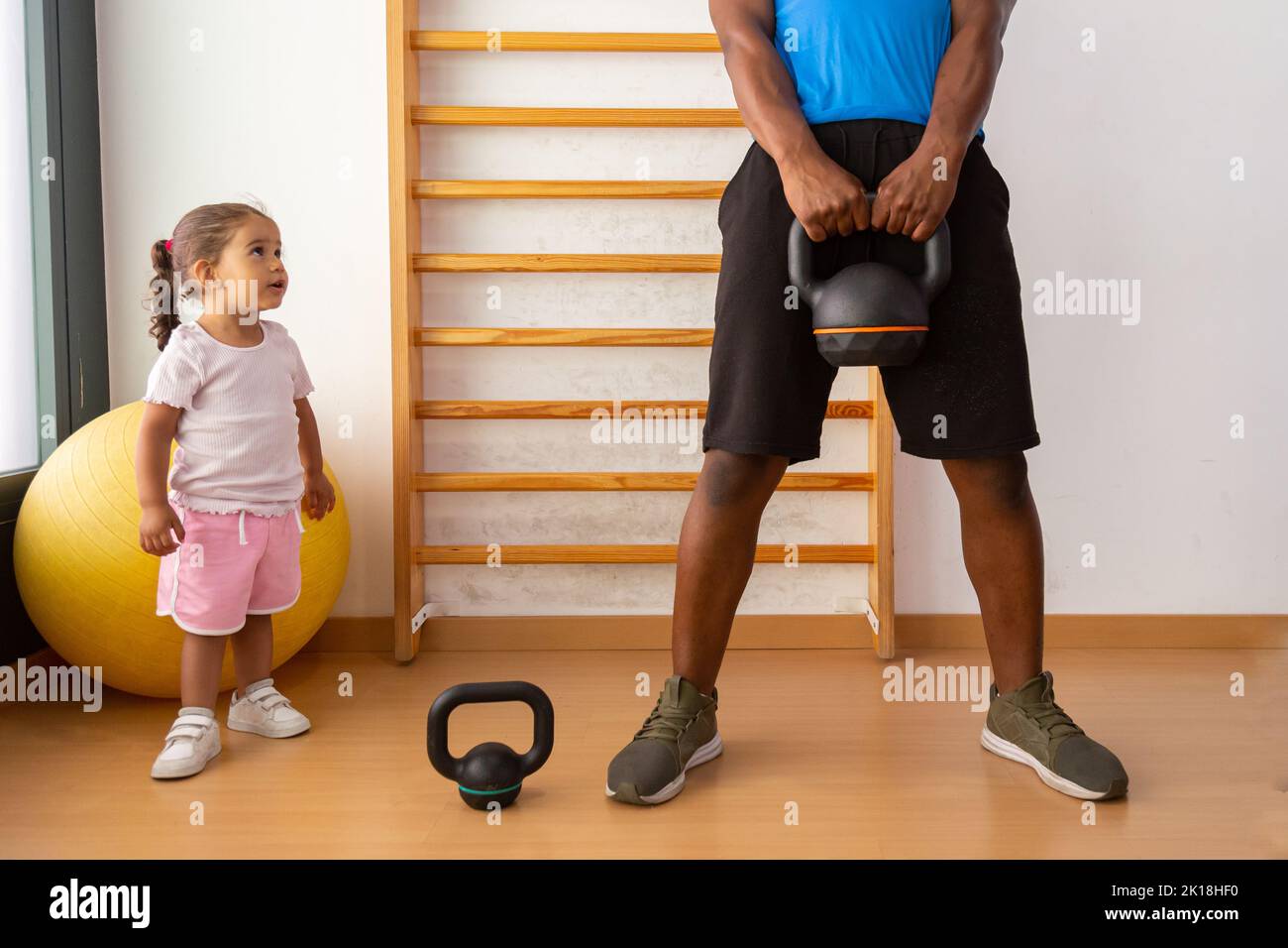 Father lifting kettlebell with his daughter Stock Photo