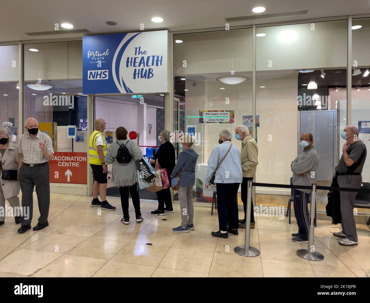 Basingstoke, Hampshire, England, UK. 2022. Elderly people standing in line at the NHS Health Hub waiting to receive an autumn booster vaccination for Stock Photo