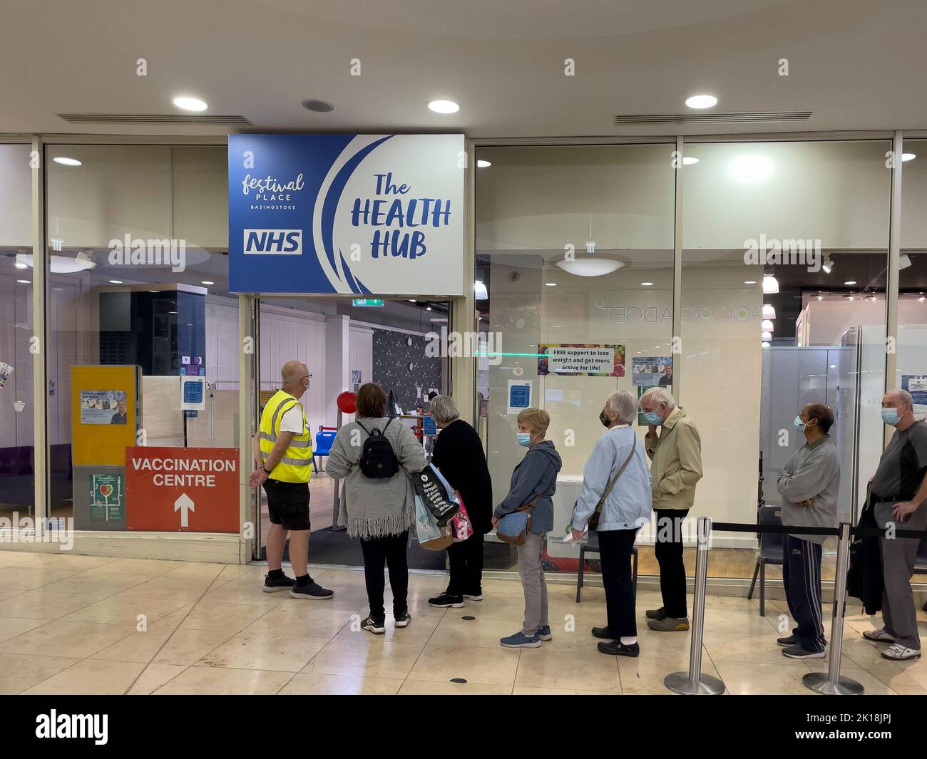 Basingstoke, Hampshire, England, UK. 2022. Elderly people standing in line at the NHS Health Hub waiting to receive an autumn booster vaccination for Stock Photo