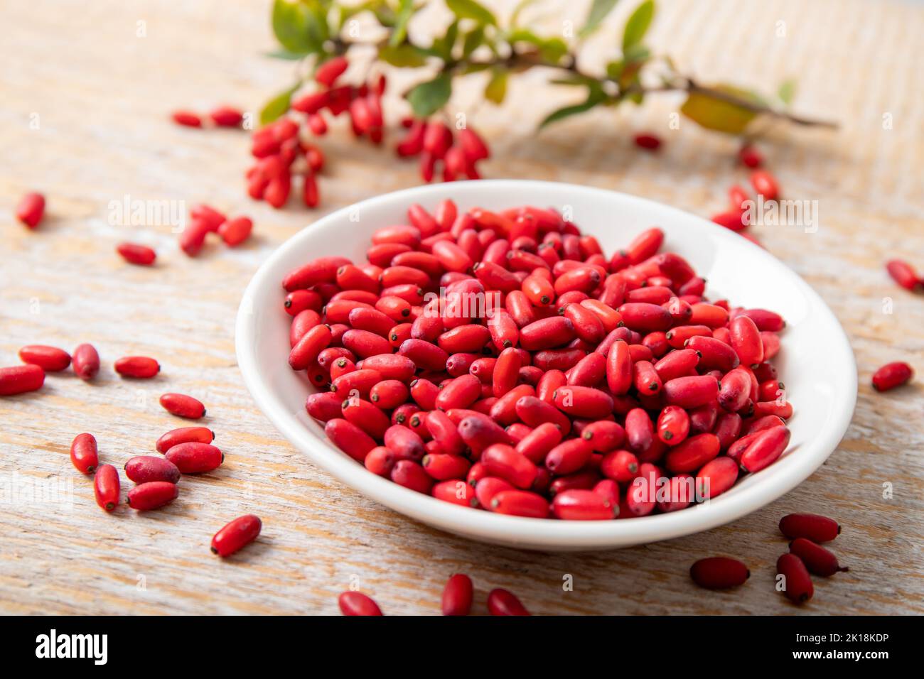 Pile of Berberis vulgaris also known as common barberry, European barberry or barberry on plate in home kicthen. Edible herbal medicinal fruit. Stock Photo