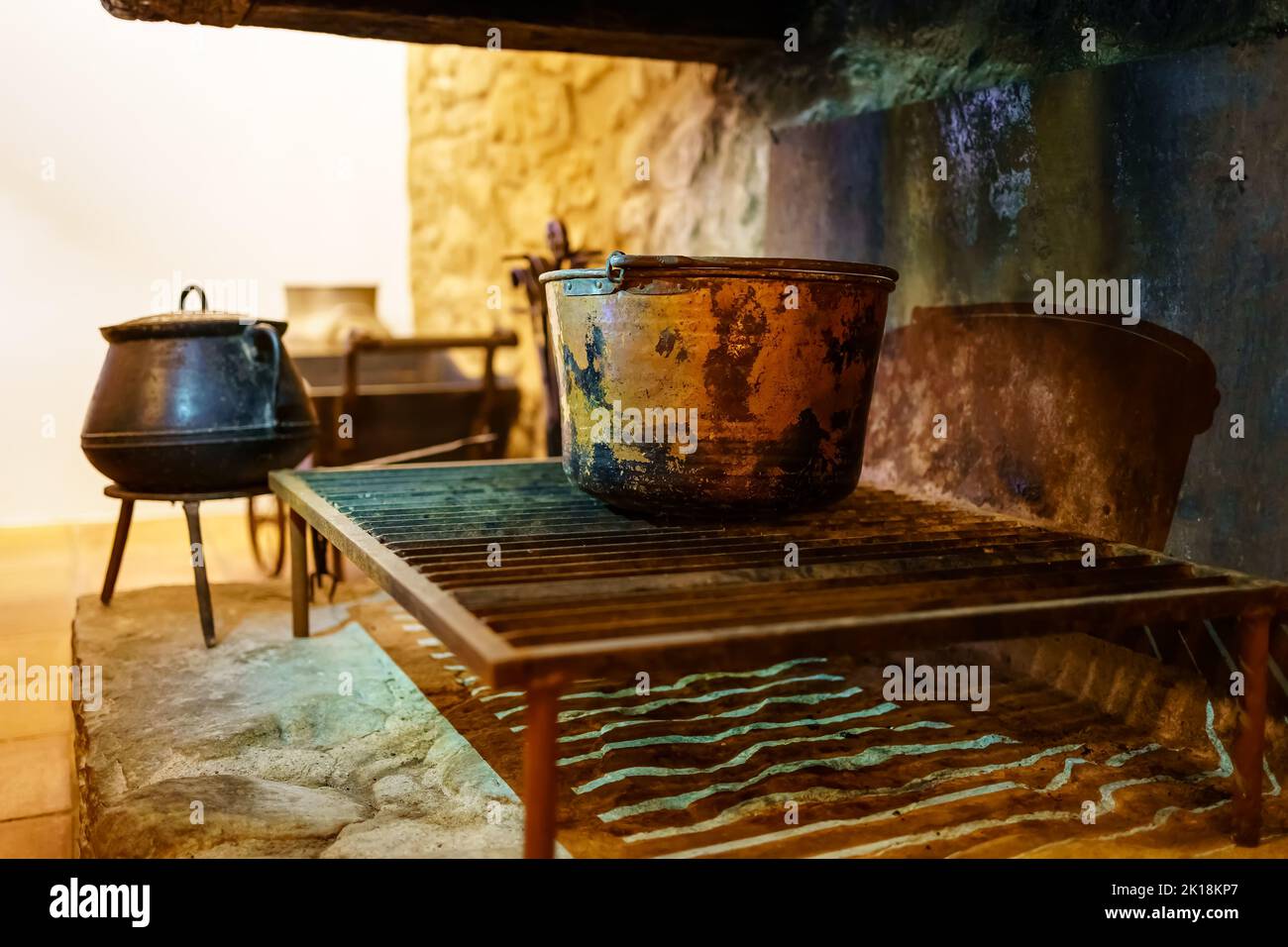 Fireplace with large pots and cooking utensils with fire in an old