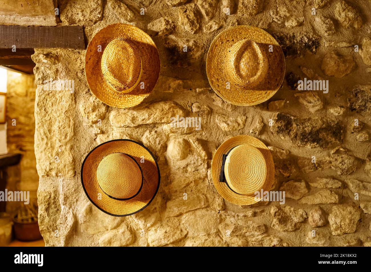 Straw hats hanging on the wall of an old retro-style house reminiscent of times gone by. Stock Photo