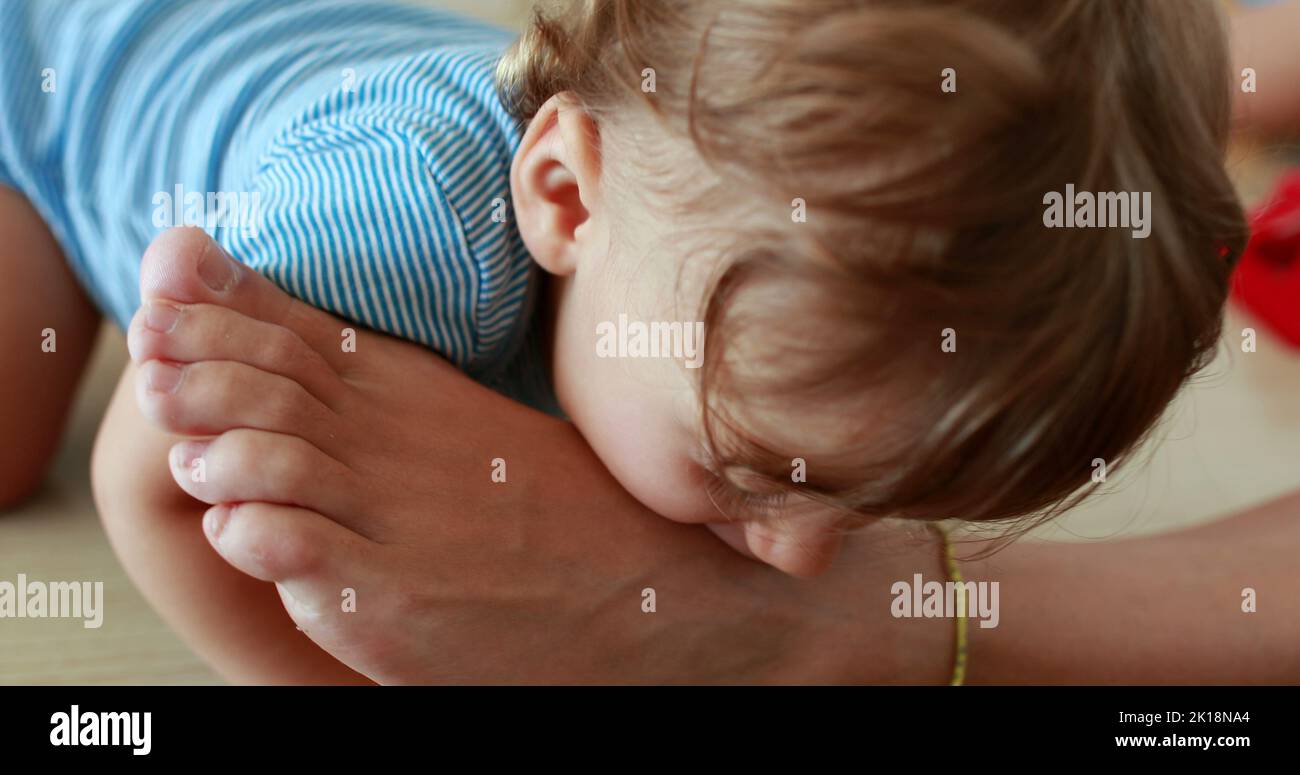 Baby biting mother feet, one year old infant child taking a bite of