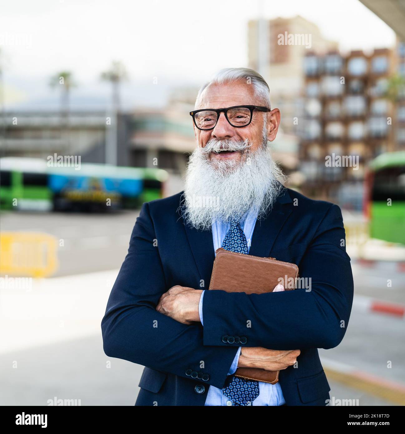 Happy senior business man holding tablet while waiting in bus station Stock Photo