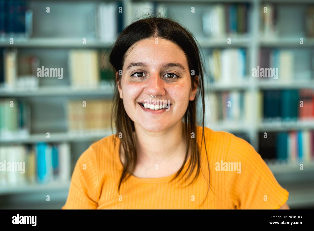 Happy young student smiling into the camera inside university library Stock Photo