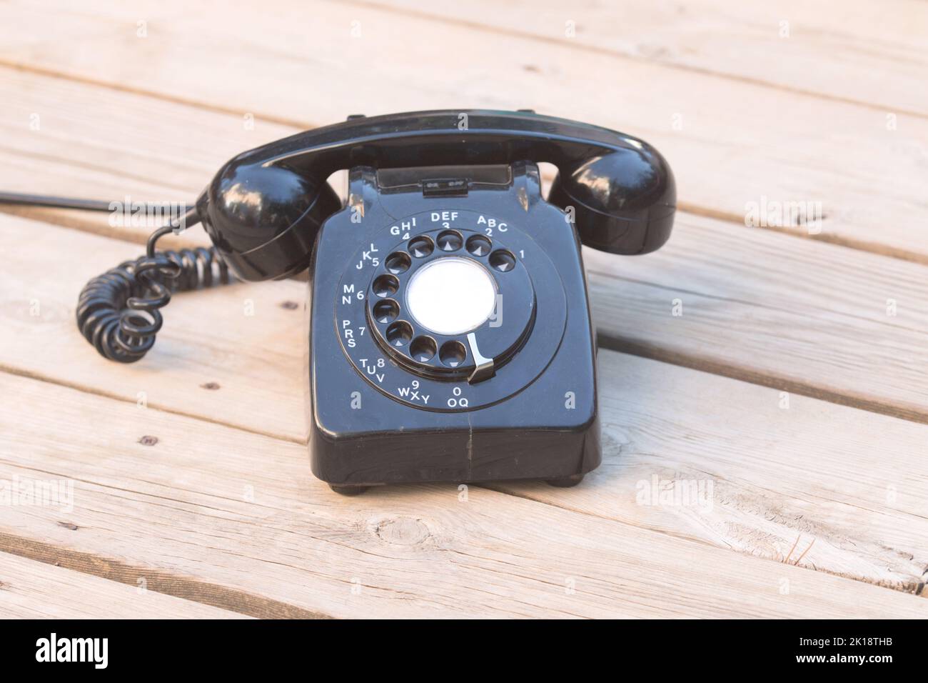 Old fashioned rotary dial telephone on wooden floorboards Stock Photo