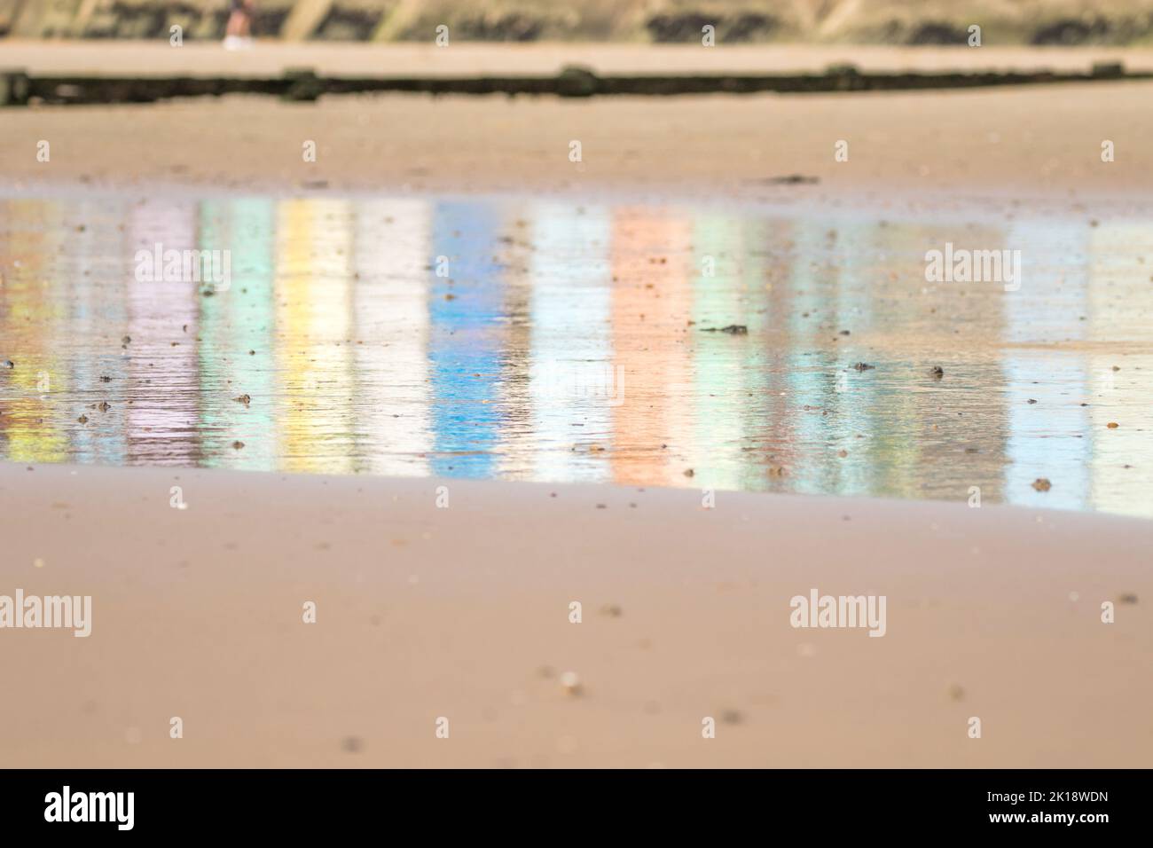 Reflections of multi-coloured beach huts on the wet sand at Walton on the naze Beach in Essex, United Kingdom Stock Photo