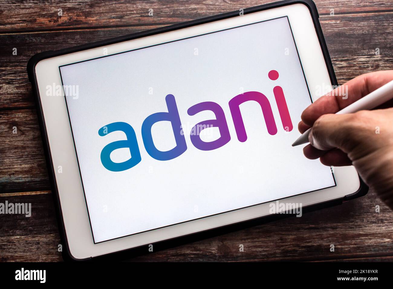 Vancouver, CANADA - Sep 16 2022 : Logo of an Indian multinational conglomerate Adani Group on tablet on wooden table. Man hand holding stylus pen Stock Photo