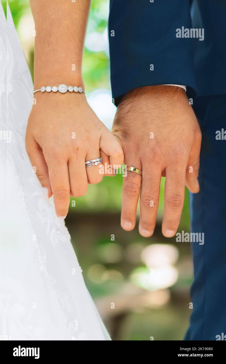 Bride and groom with wedding rings, little fingers locked together ...