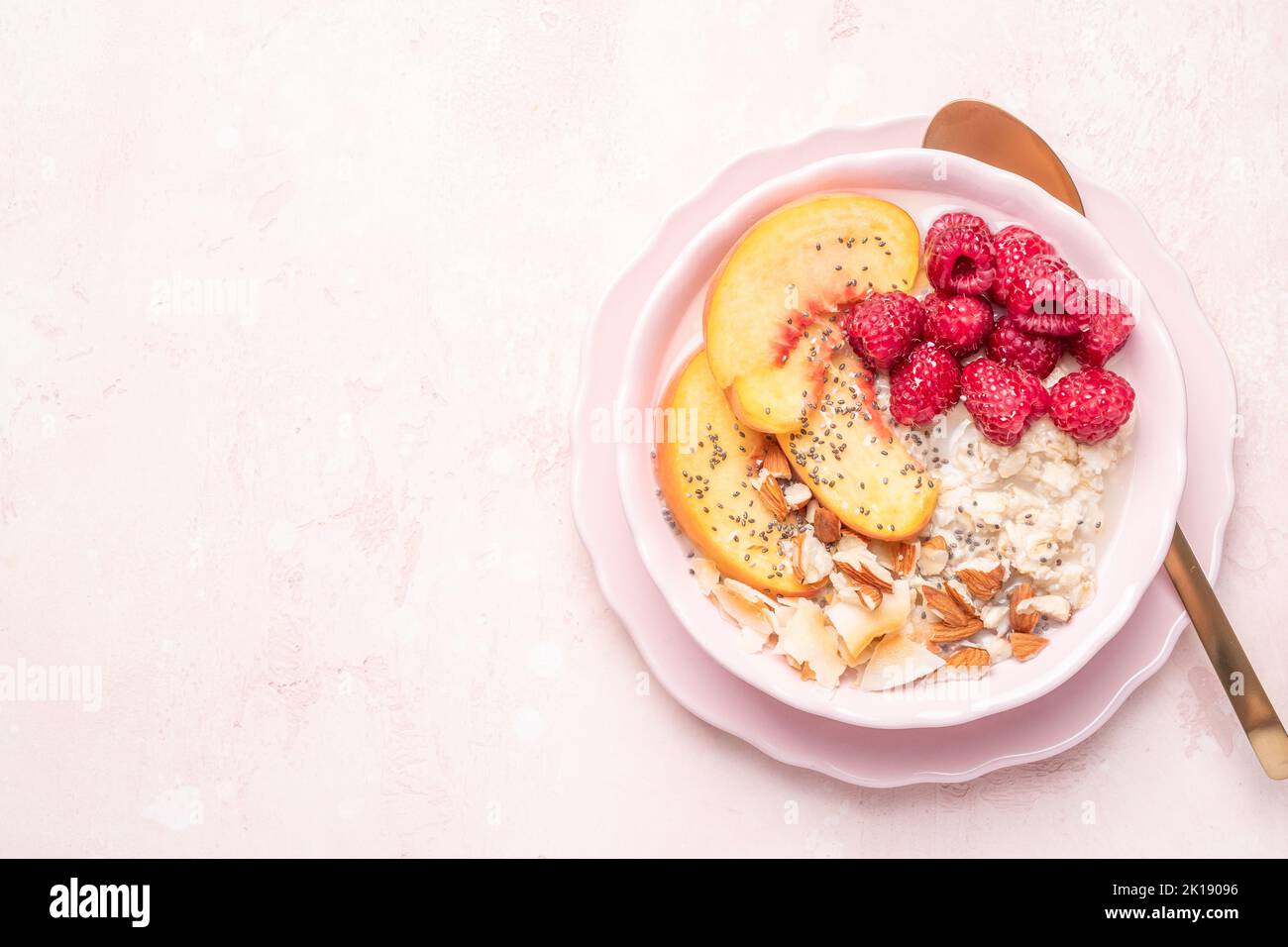 Porridge oatmeal with raspberries, peaches and nuts Stock Photo