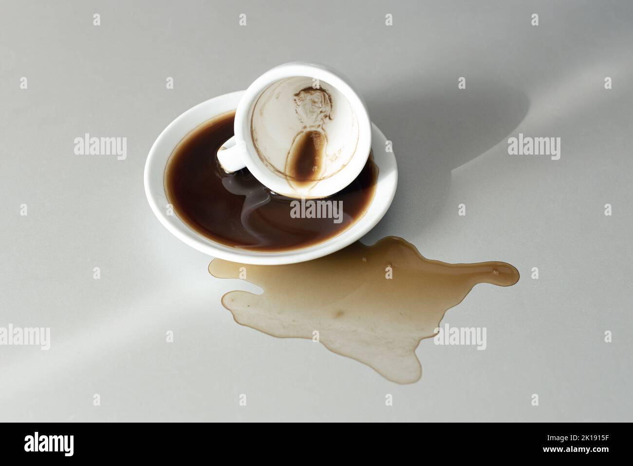 Spilled coffee on gray table. White coffee cup lying down Stock Photo