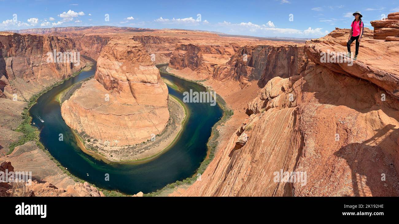 Young girl tourist standing on the ridge of Horseshoe Bend on the Colorado River near Page Arizona on sunny late morning Stock Photo