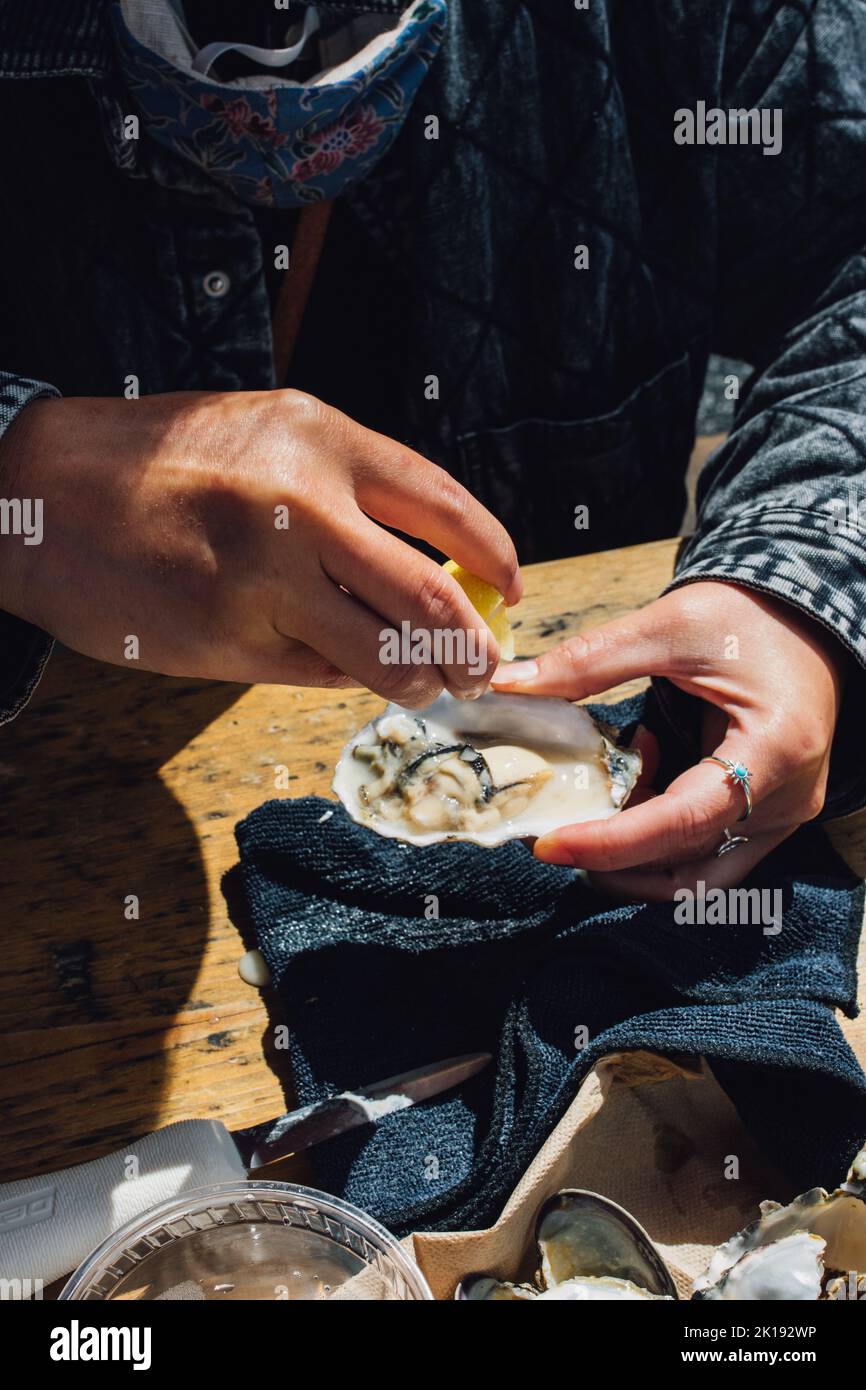 woman shucking and eating oysters at outdoor restaurant Stock Photo Alamy