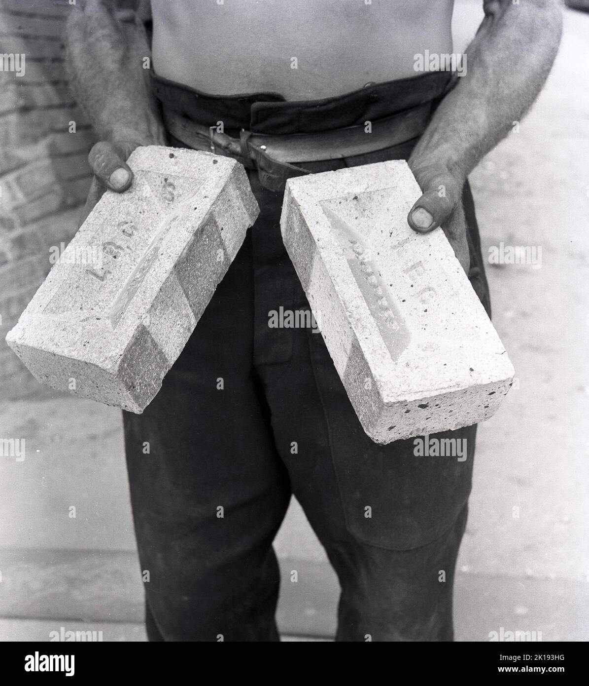 1950s, historical, a male worker holding in his hands two bricks, imprinted with the letters L.B.C, made at the brickworks of the London Brick Company, Stewartby, Bedfordshire, England, UK.  Founded in 1900, the London Brick Company specialised in making 'fletton' bricks, a name given generally to bricks made from Lower Oxford Clay, which has the benefit of containing carbon, providing part of the fuel required in firing. Stock Photo