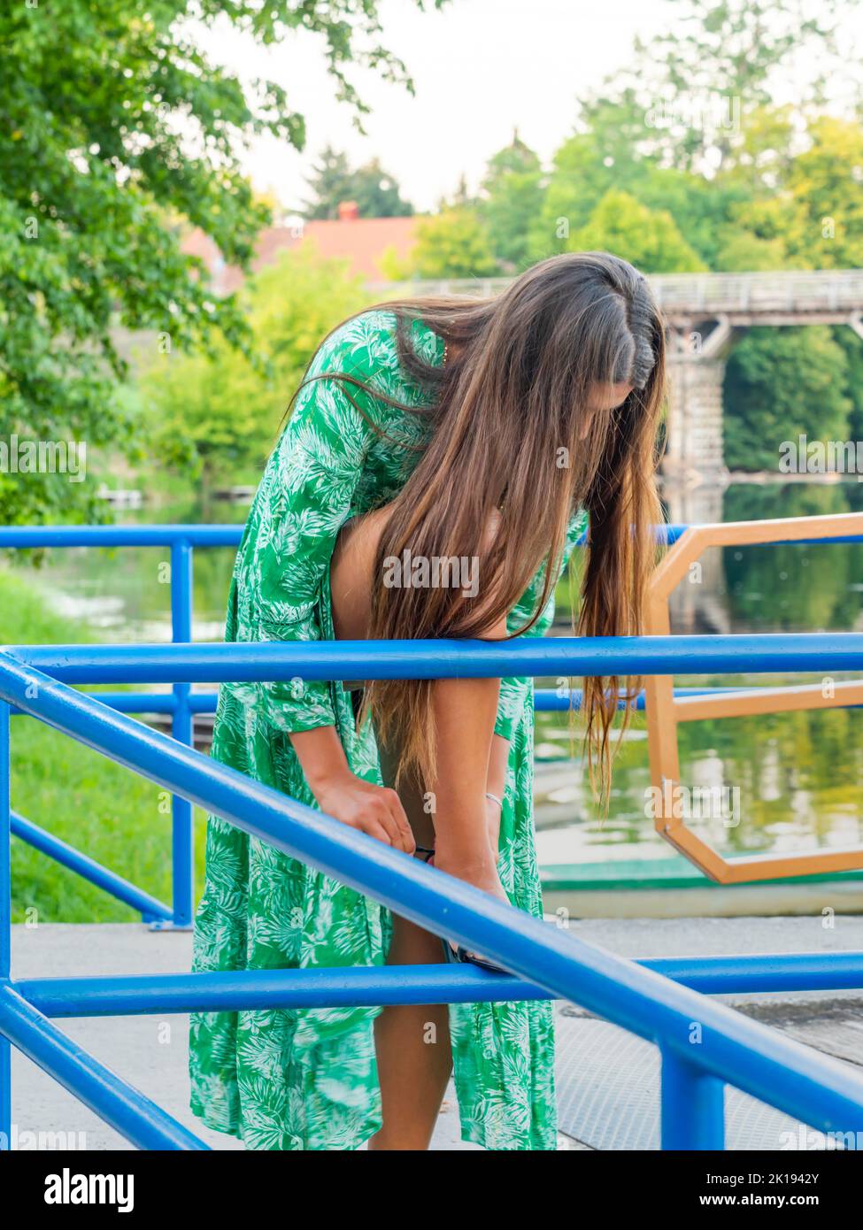 Young woman outside outdoors awkward position situation tying her high-heels Stock Photo