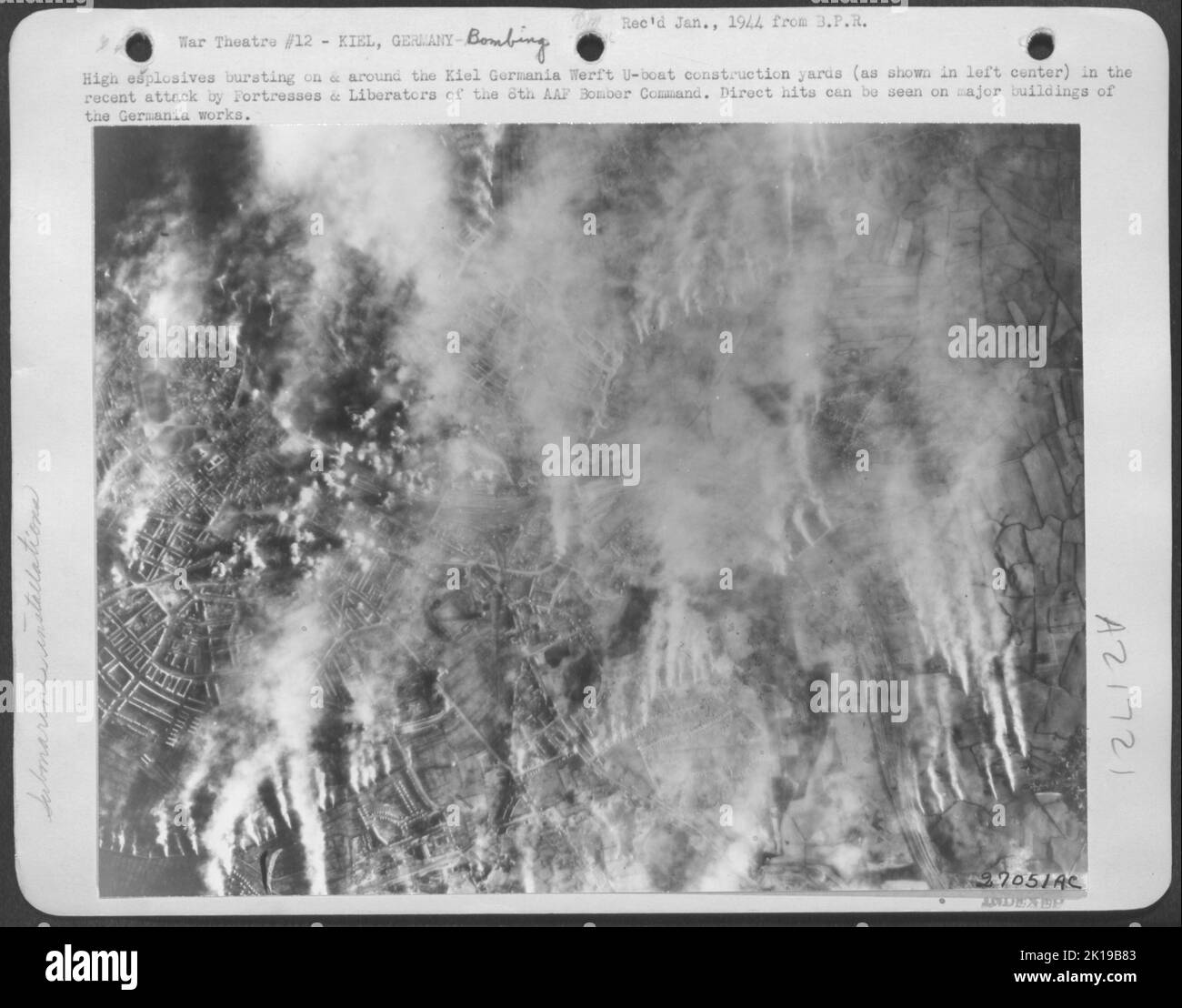 High explosives bursting on and around the Kiel Germania Werft U-boat construction yards (as shown in left center) in the recent attack by Fortresses and Liberators of the Eighth AAF Bomber Command. Direct hits can be seen on major buildings of the Stock Photo