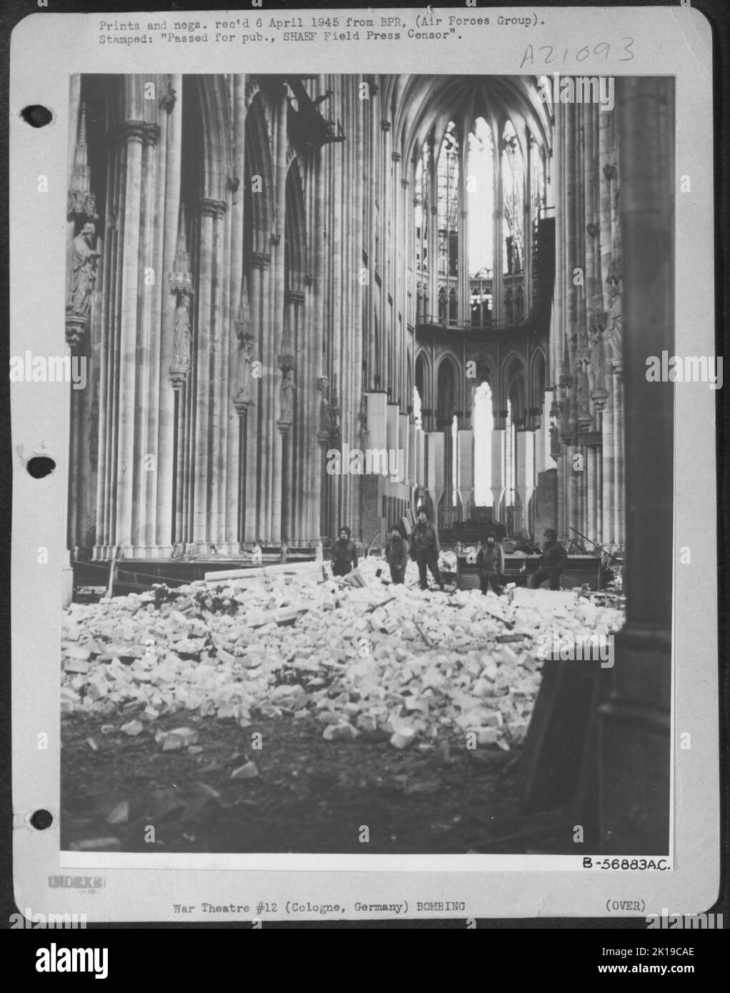 American infantrymen standing knee-deep in rubble view the damage inside the Cologne Cathedral in Germany. During the repeated attacks by Allied Air Forces, the structure was not hit. The concussion caused by the bombing of the nearby railroad Stock Photo