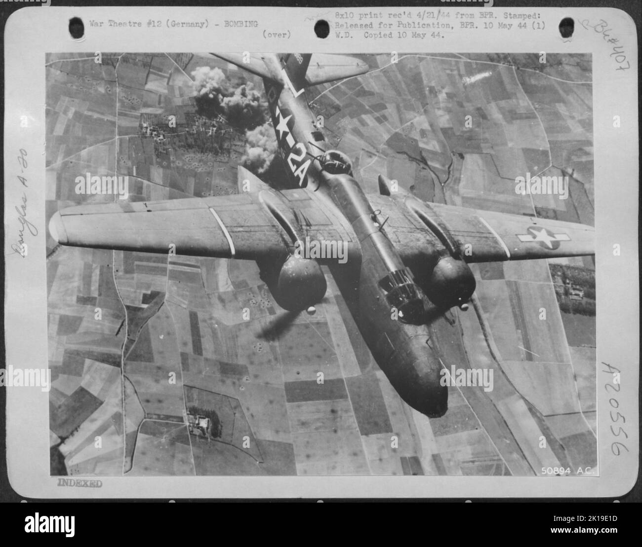 Leaving a target several thousand feet below engulfed in smoke and flames, a trim, speedy A-20 Havoc light attack bomber of the U.S. 9th A.F. is shown streaking for its base in England after a recent attack against one of Hitler's defenses on the Stock Photo