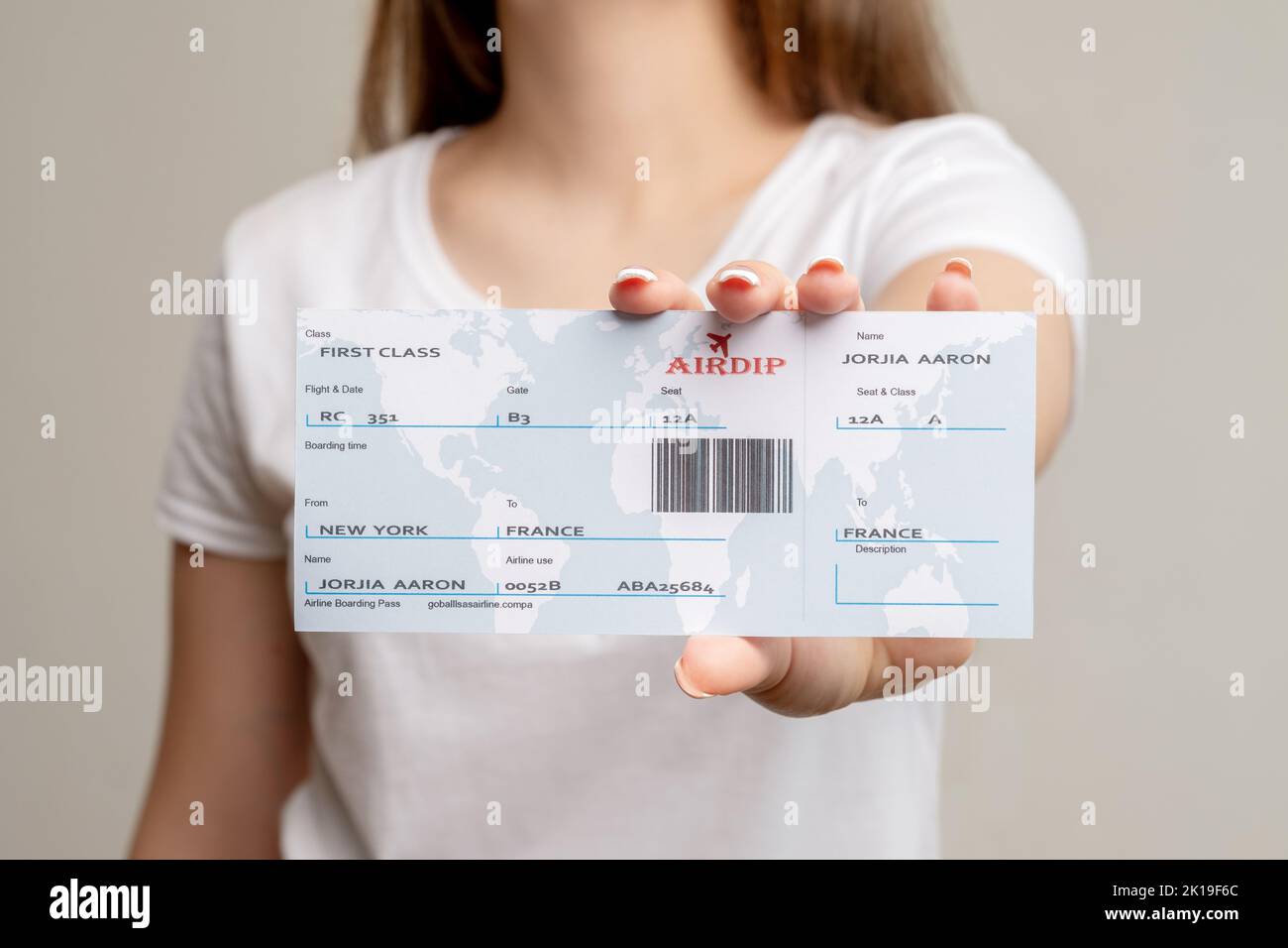 Flight ticket. World trip. Tourist woman showing American citizen first class boarding pass to France isolated on blur neutral background. Global trav Stock Photo