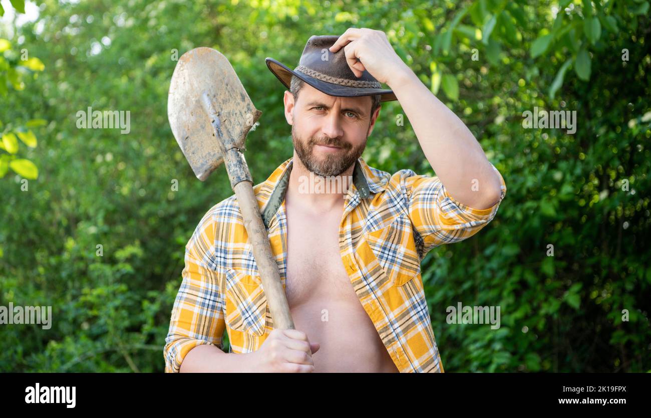 Happy cowboy man tipping cowboy hat holding shovel. Cowboy smiling in ...