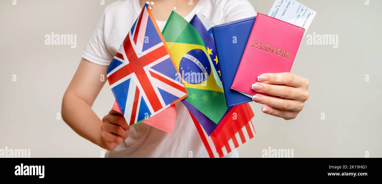 Global travel. World trip. Tourist woman showing id passport in pink blue cover flight ticket international flags isolated on blur neutral background. Stock Photo
