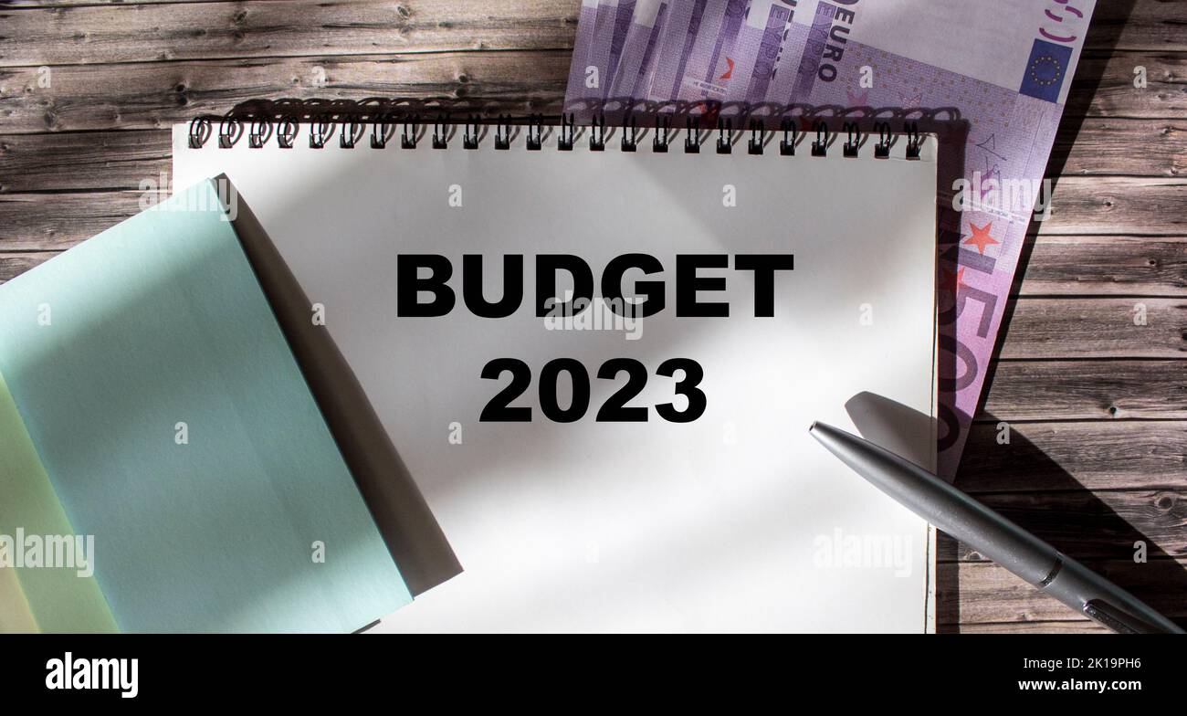 Budget 2023 text message with stickers, pen and euro banknotes on wooden background Stock Photo