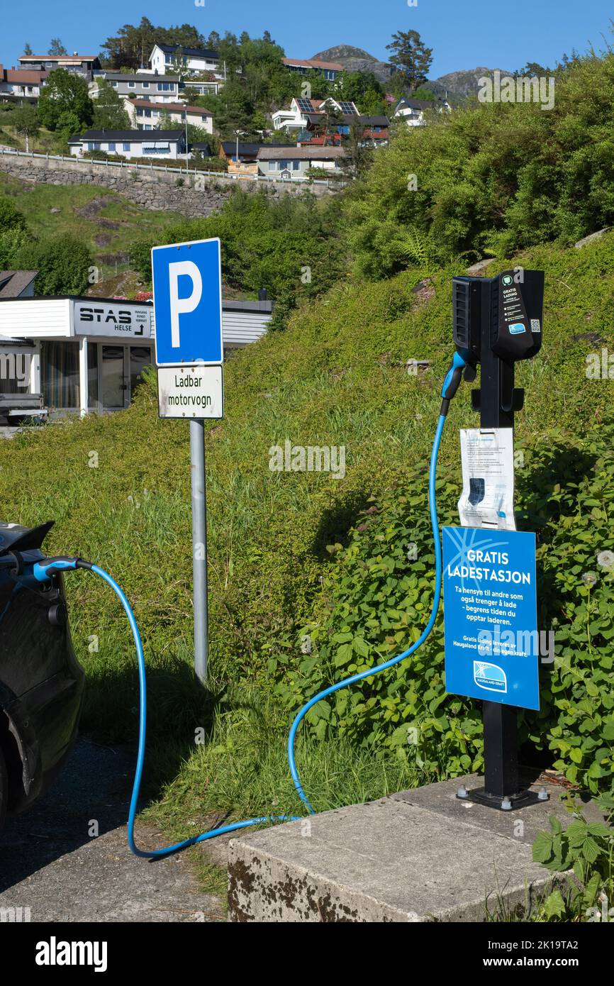 Sand, Norway - June 6, 2022: A static shot of a solid black Tesla Model 3 dual motor charging at the Haugaland Kraft AC charging station in a rainy sp Stock Photo