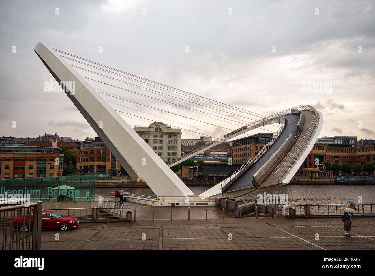 The Gateshead Millennium Bridge opening on a wet day, looking towards the quayside from the Gateshead river bank Stock Photo