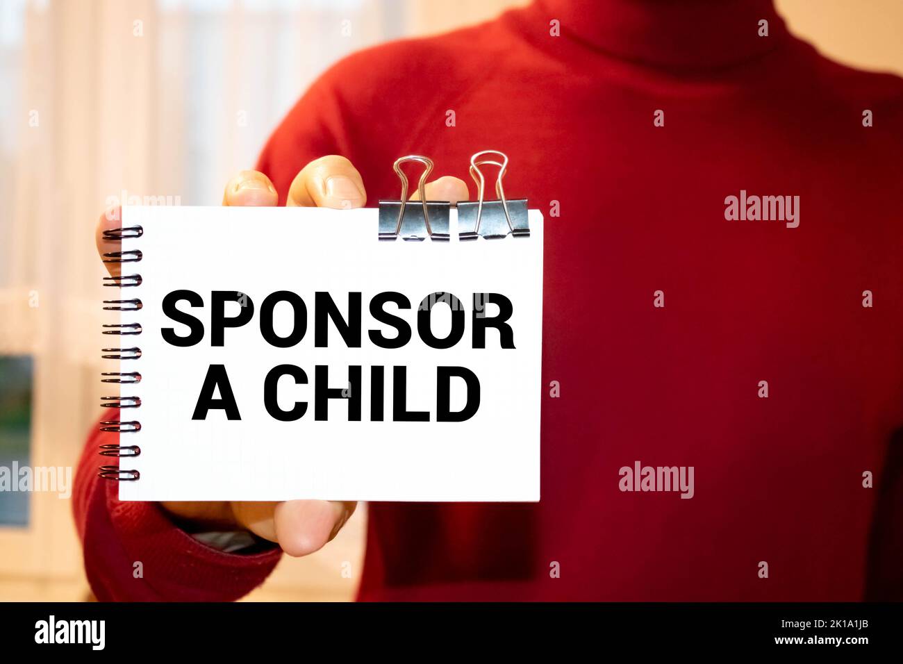 Sponsor A Child text written on a notebook with pencils Stock Photo