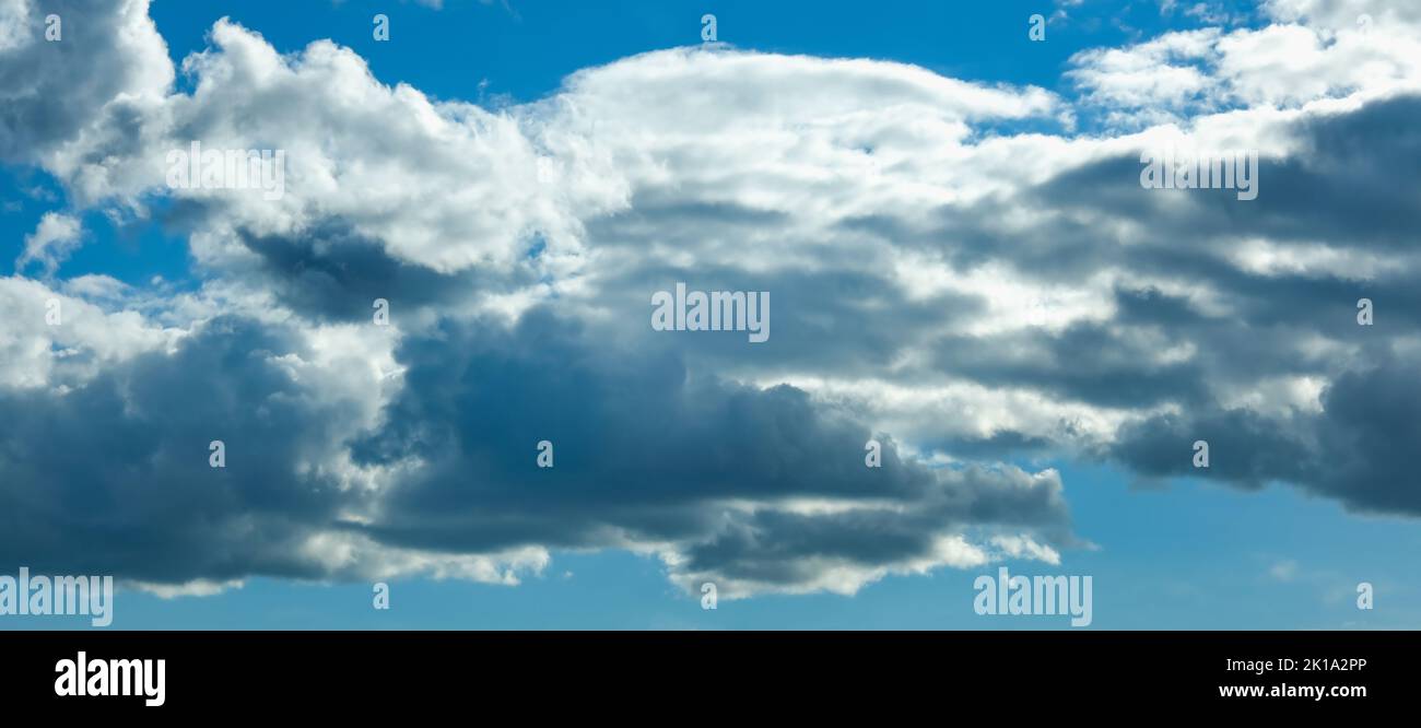 Blue sky with thunderclouds. The sun breaks through the clouds. Black clouds. Banner. Stock Photo