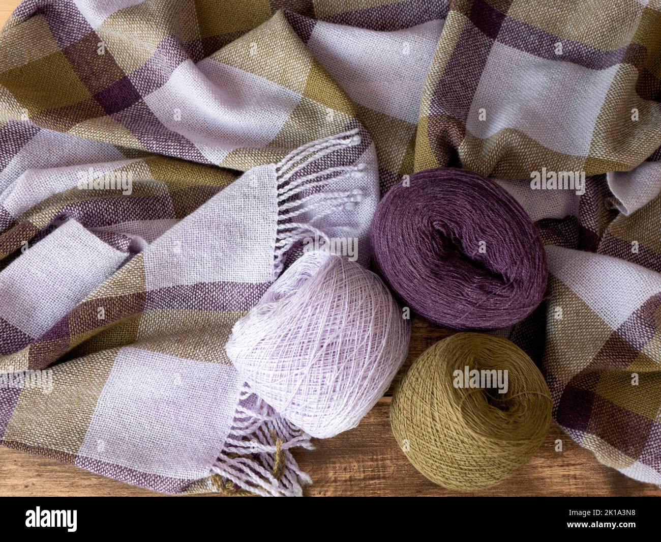 Yarn balls of olive, purple and violet colors and soft and cozy shawl