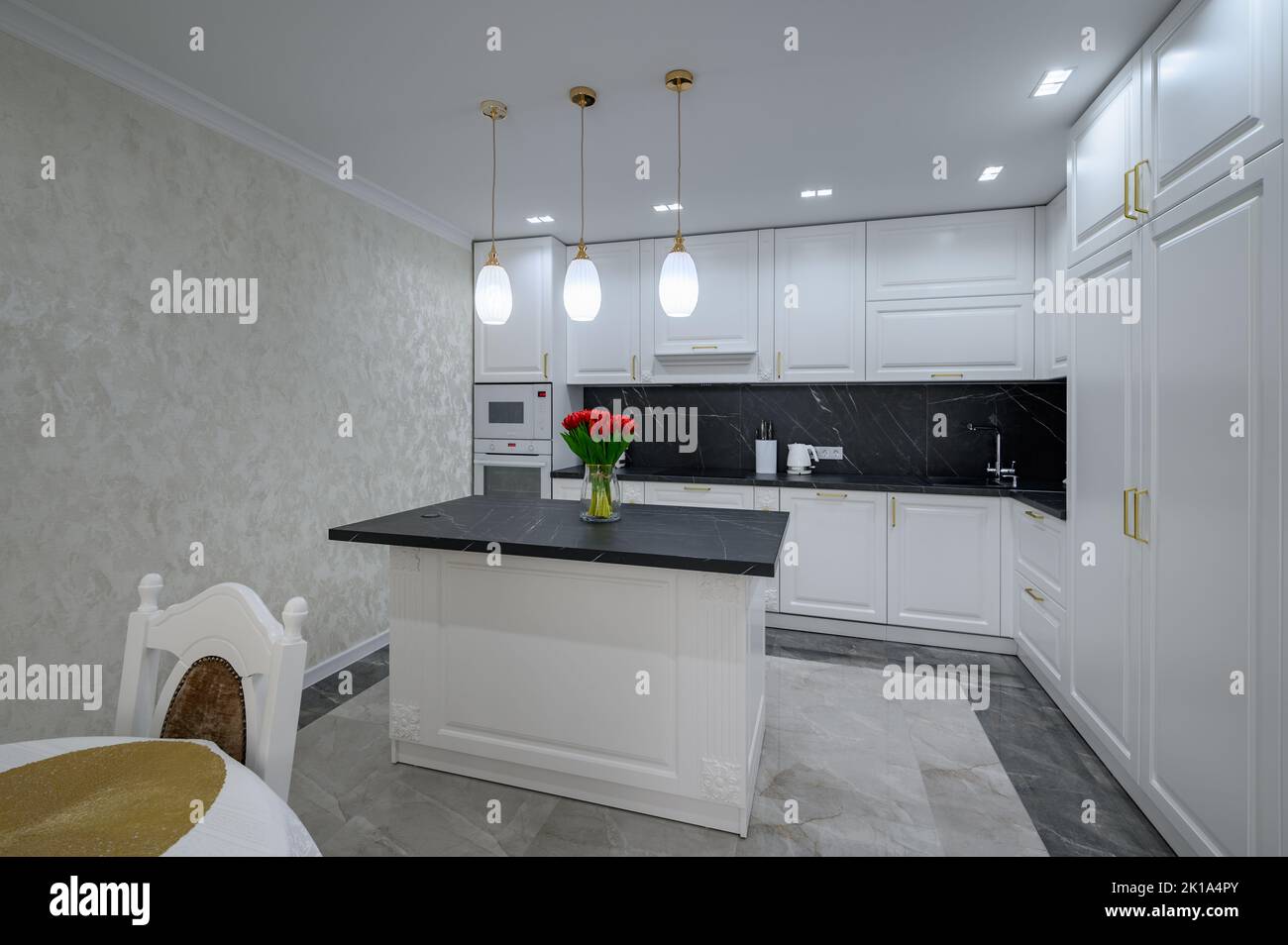 White modern domestic kitchen with island and black marble worktop Stock Photo