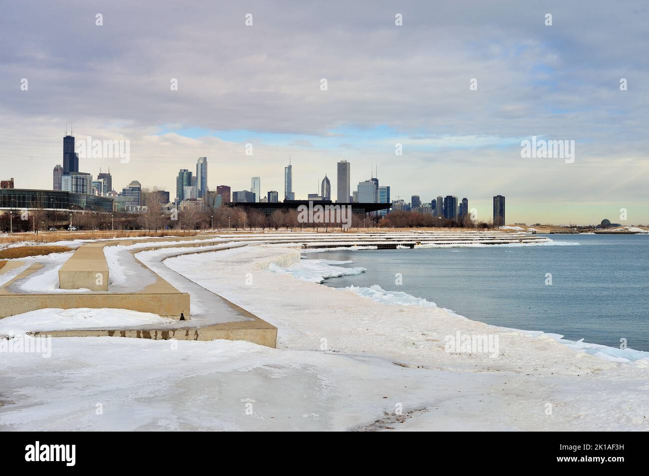 Ice and snow cling to the lake wall along Lake Michigan in Chicago in late February on a day filled with ominus clouds. Past the frozen scene in the n Stock Photo