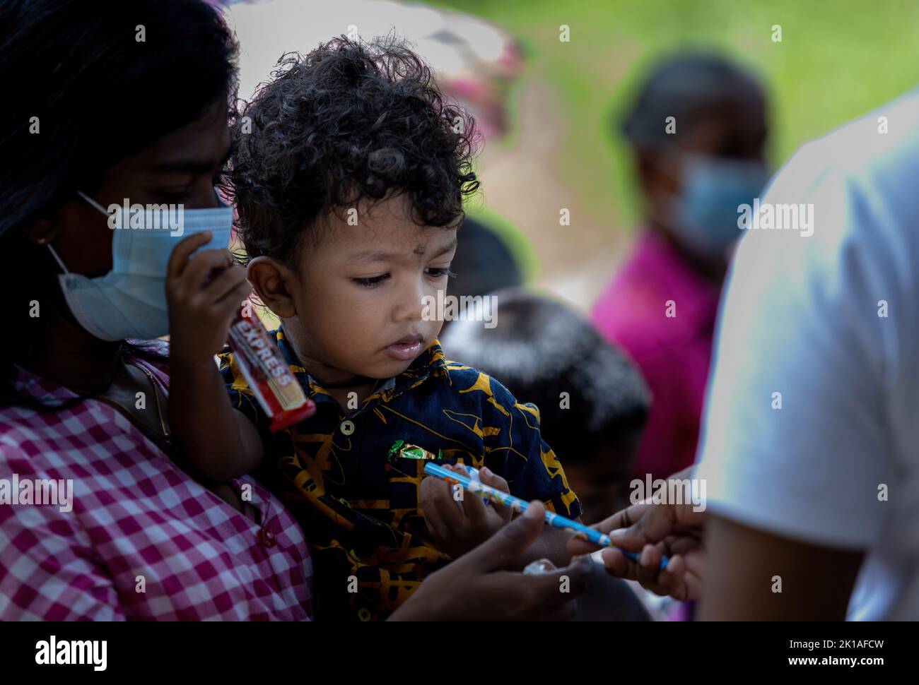 small child holding a pencil while mom is carrying in hand in Sri Lanka 30th July 2022 Stock Photo