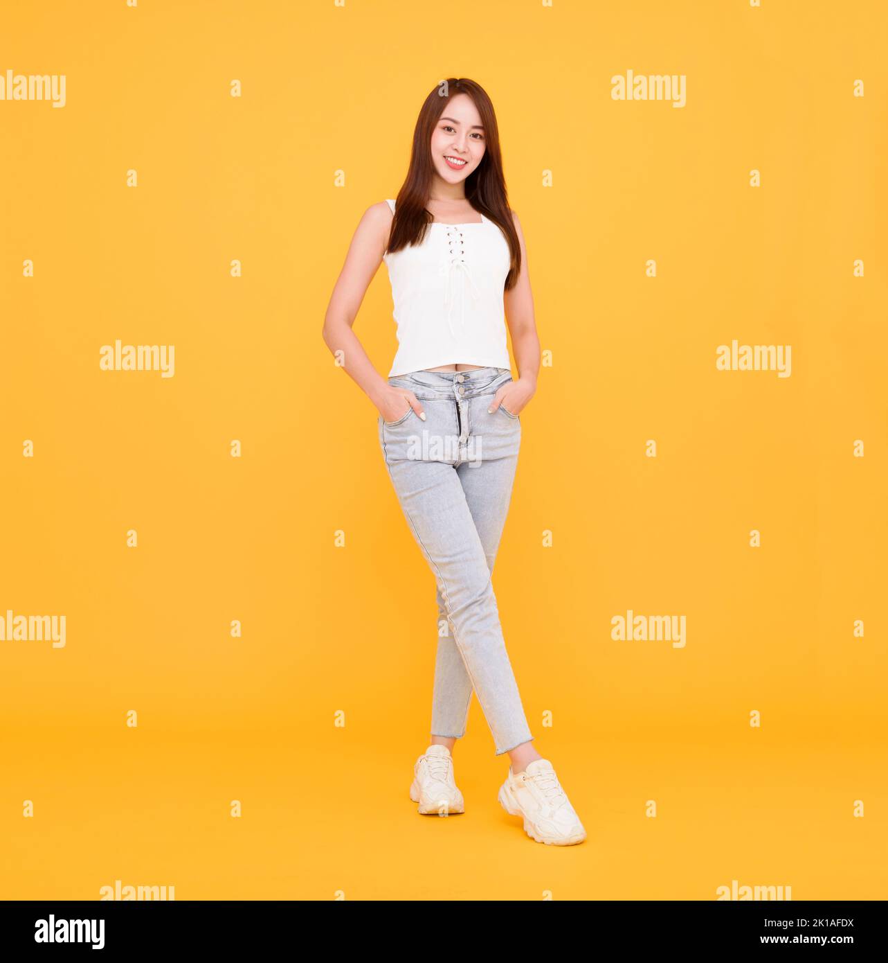 Full length of Happy  young woman  standing  isolated over yellow Stock Photo