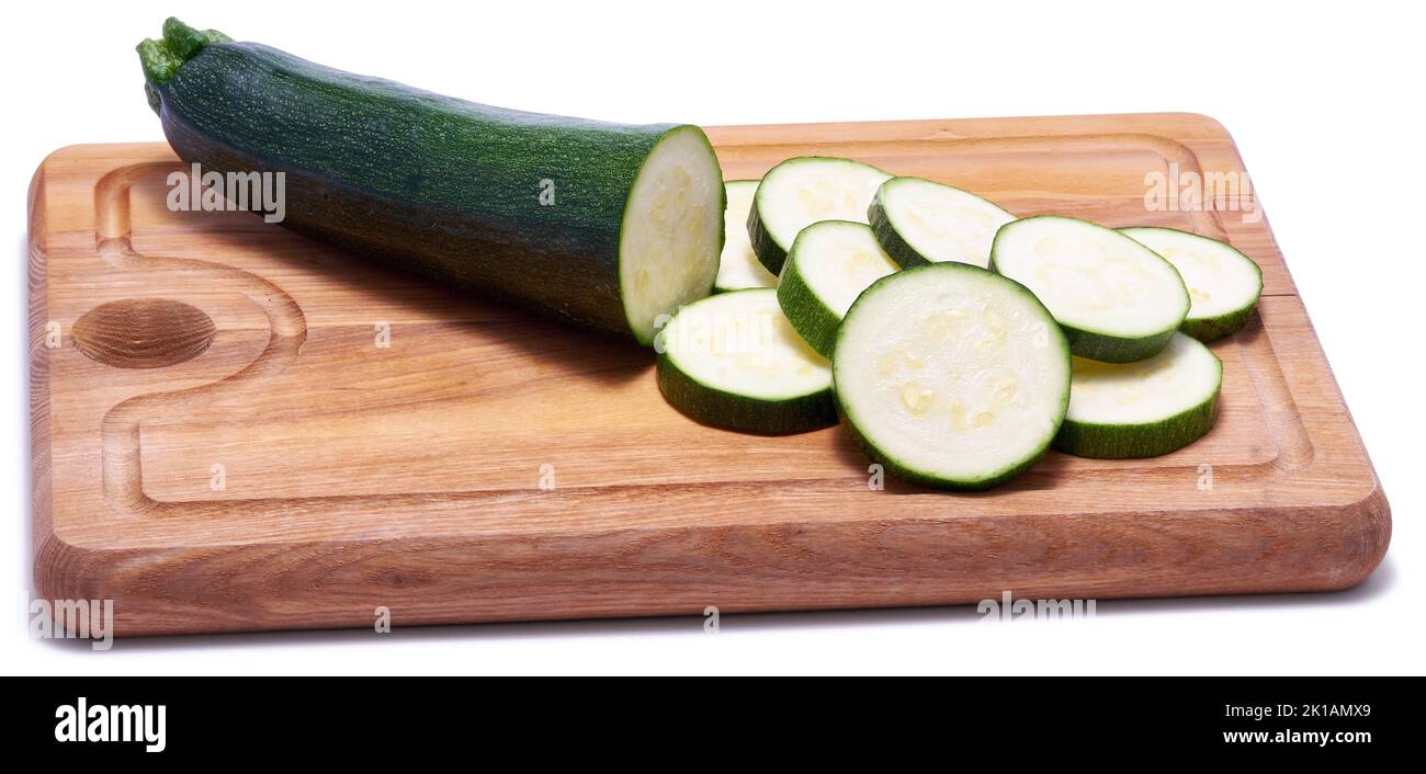 Sliced zucchini circles on wooden cutting board isolated on white background Stock Photo