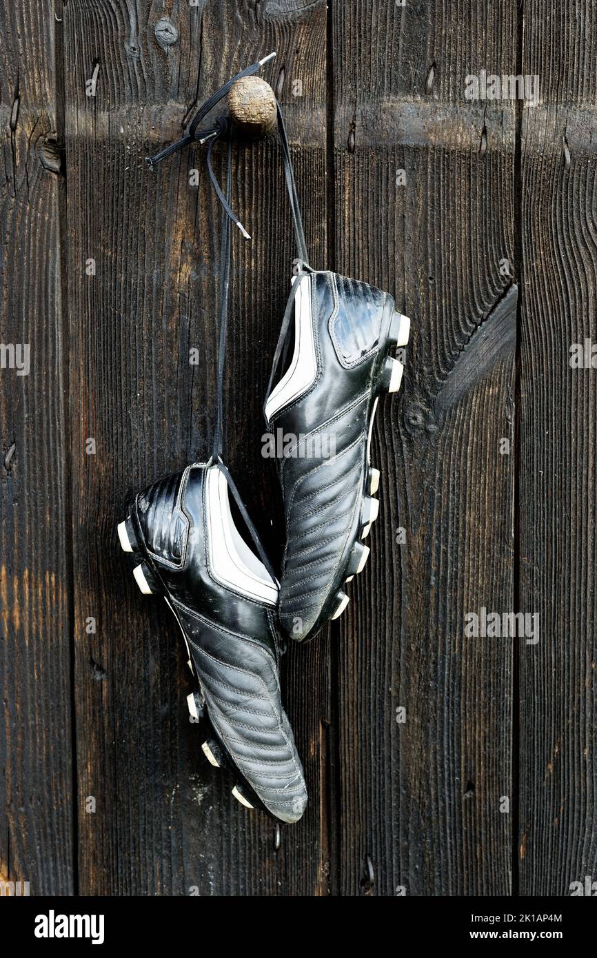A pair of soccer boots hanging on a wooden wall. The end of the football career Stock Photo