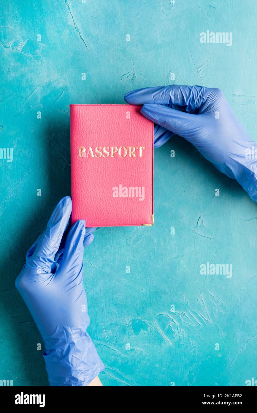 Passport control. Traveling restriction. Hands in protective gloves holding foreign id on blue copy space. Pandemic prevention. Hygiene measures. New Stock Photo