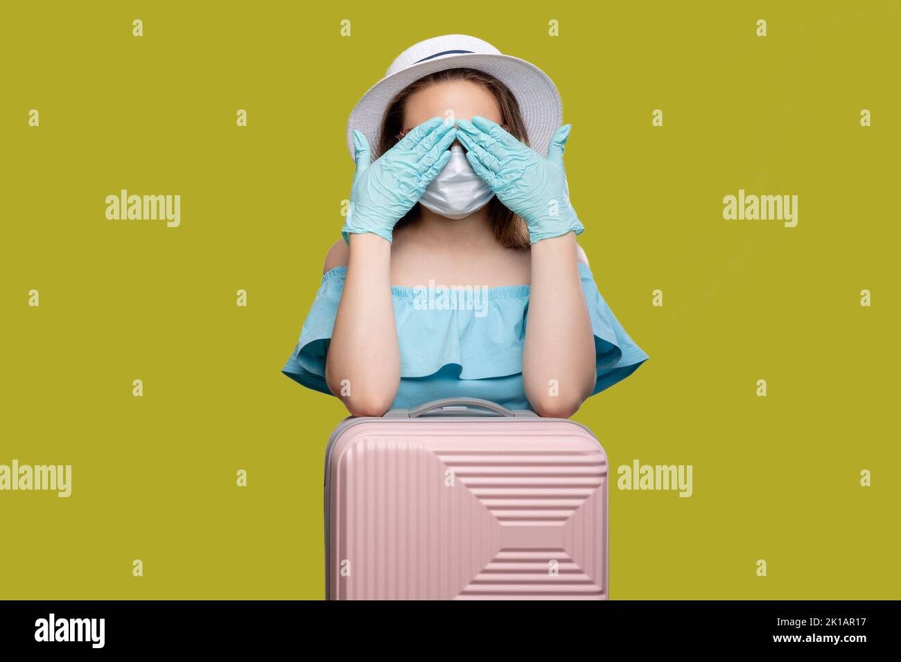 Borders opened. COVID-19 prevention. Woman with suitcase closing eyes by hands. Isolated on yellow copy space. Pandemic recovery. Summer journey Stock Photo