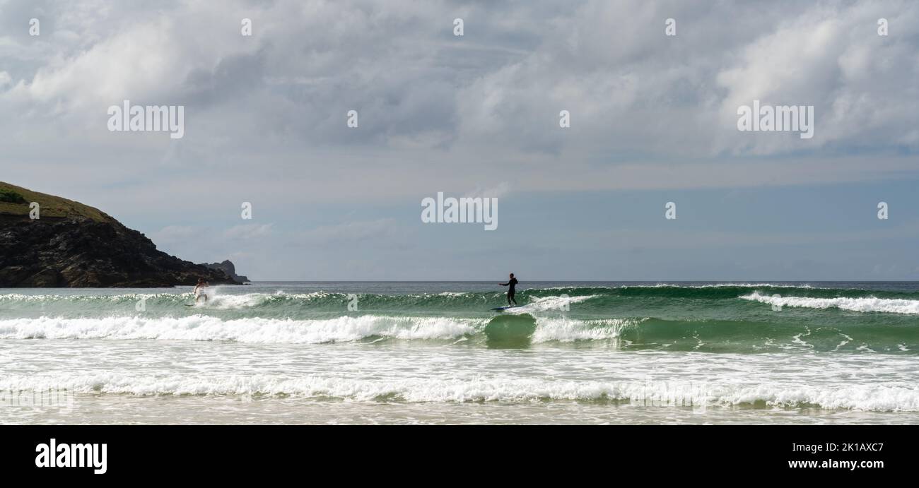 Newquay, United Kingdom - 4 Spetember, 2022: panorama landscape of Fistral Beach in Newquay with surfers catchign waves on a sunny late summer day Stock Photo