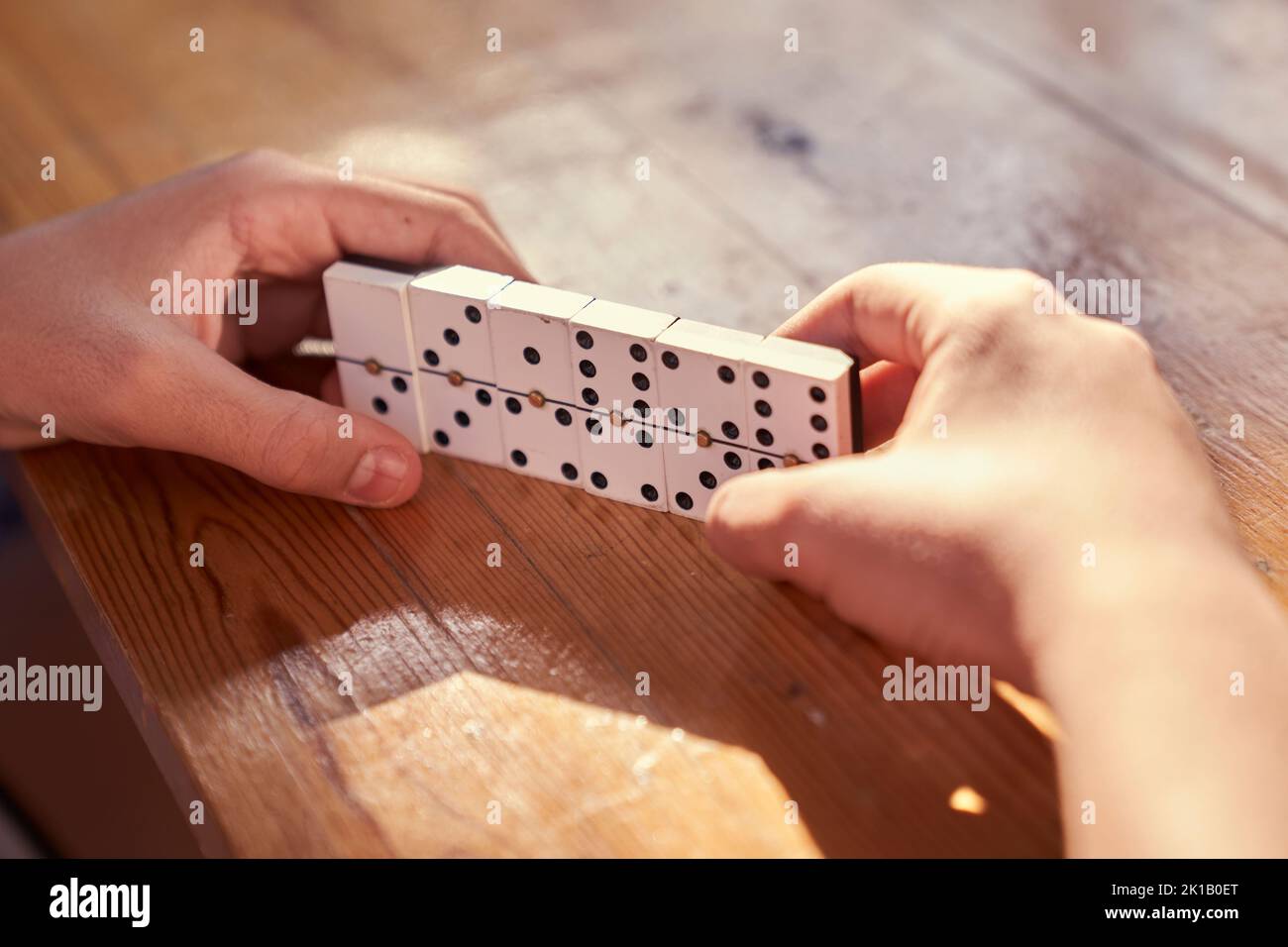 A family playing domino game in a wooden table. Stock Photo