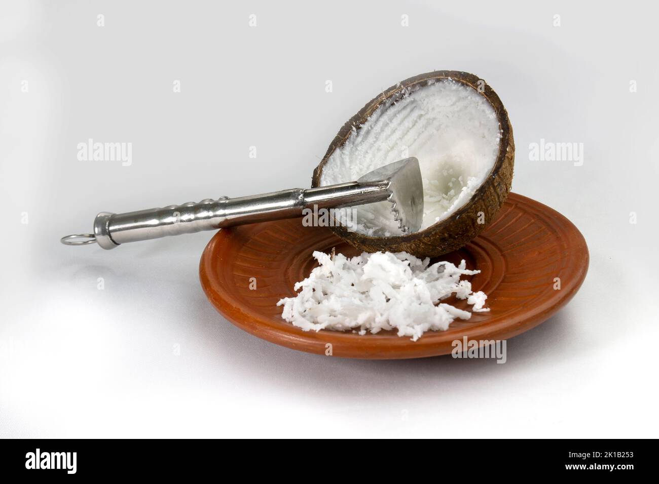 https://c8.alamy.com/comp/2K1B253/grated-coconut-in-a-mud-plate-with-a-coconut-hand-grater-on-white-background-2K1B253.jpg