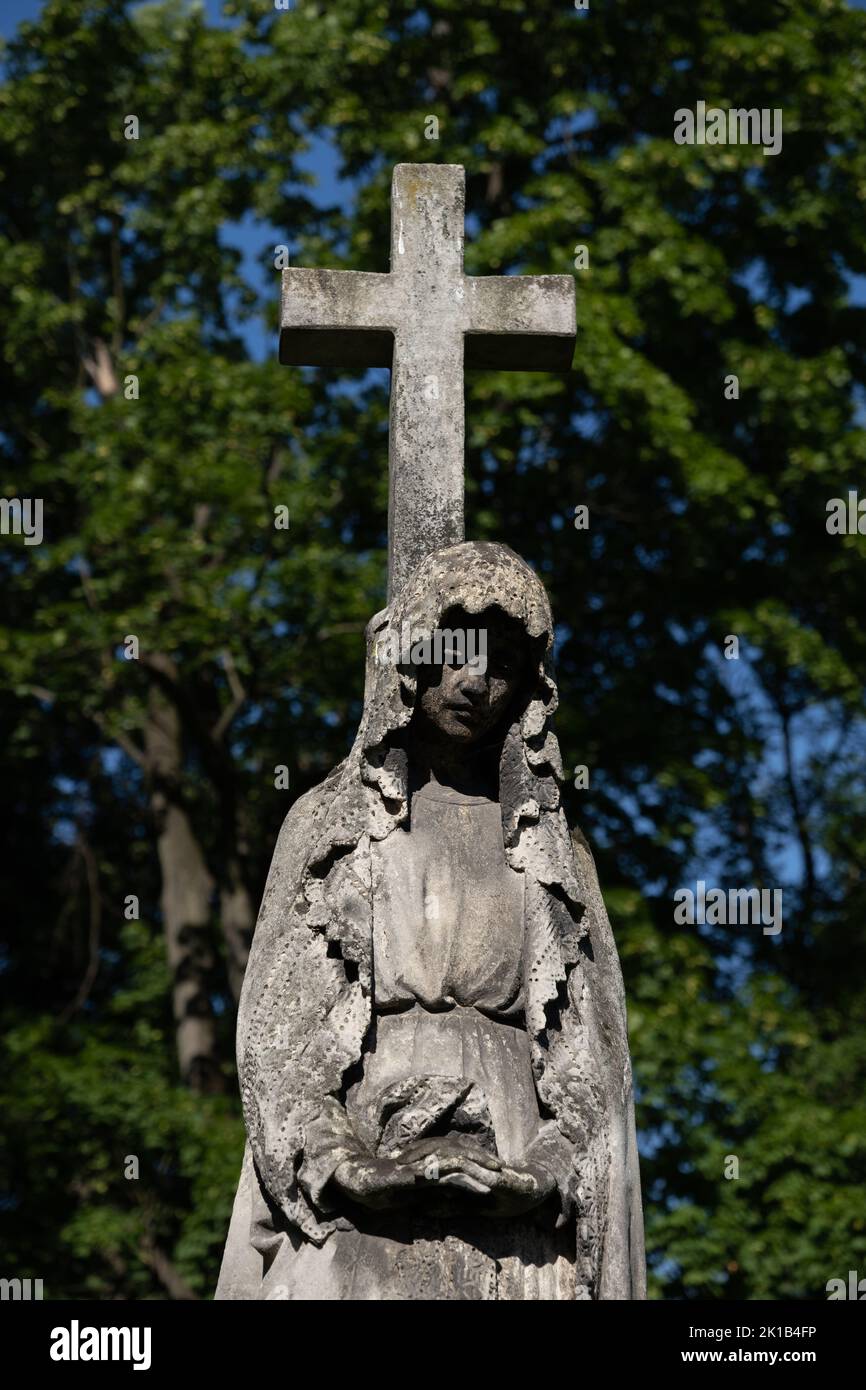 Saint Mary with cross cemetery sculpture, old statue in historic necropolis. Stock Photo