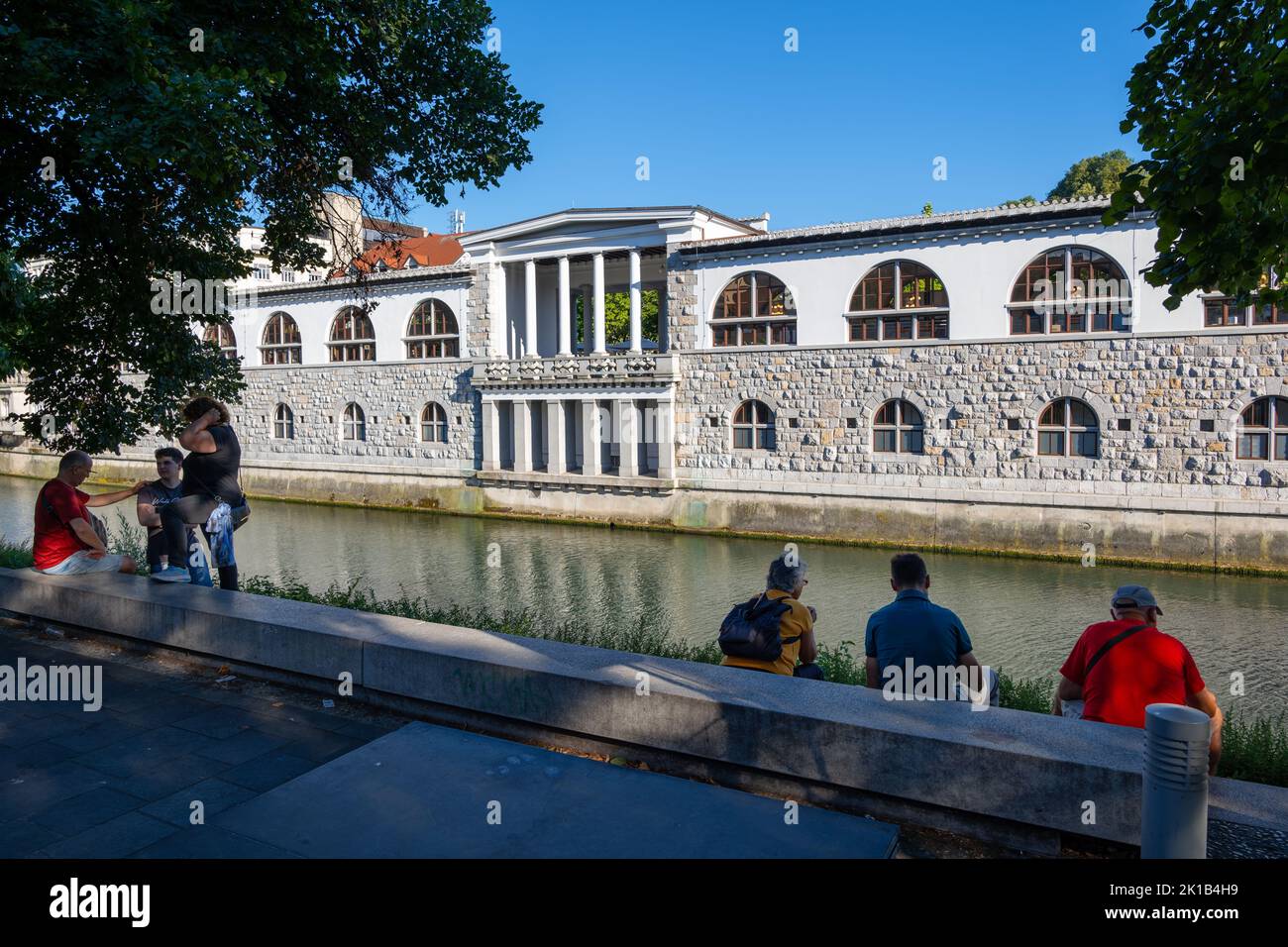 City of Ljubljana in Slovenia, people at Ljubljanica River waterfront looking at the Plecnik Arcades, city landmark. Stock Photo
