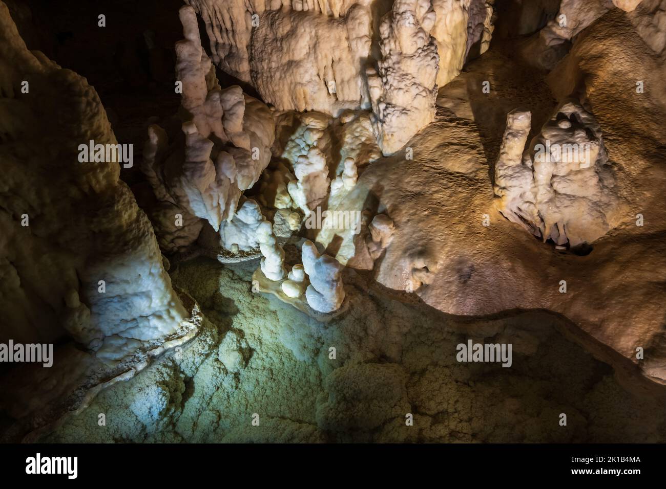 Smooth rock formations and water pool in Postojna Cave scenic interior in Slovenia. Stock Photo