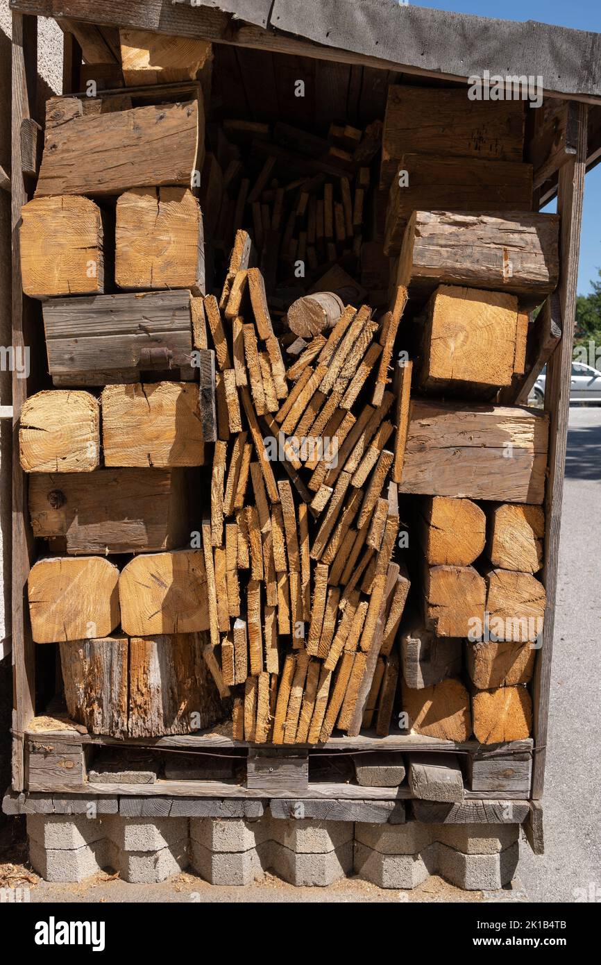 Log store with wood logs, planks and boards store, firewood supply for cold season in garden yard. Stock Photo