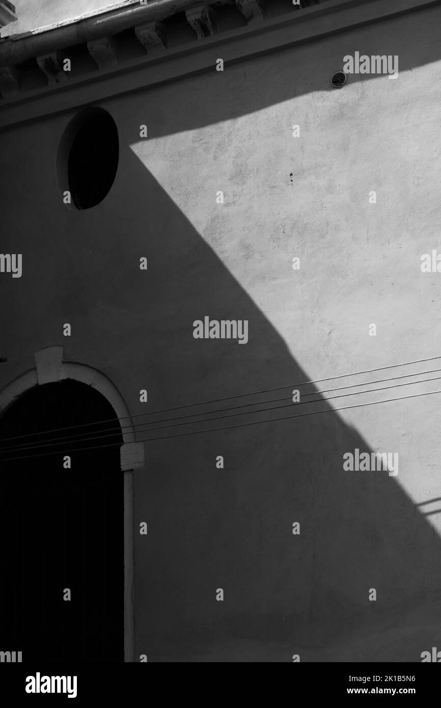 A vertical grayscale shot of the shadows on the wall of a house Stock Photo