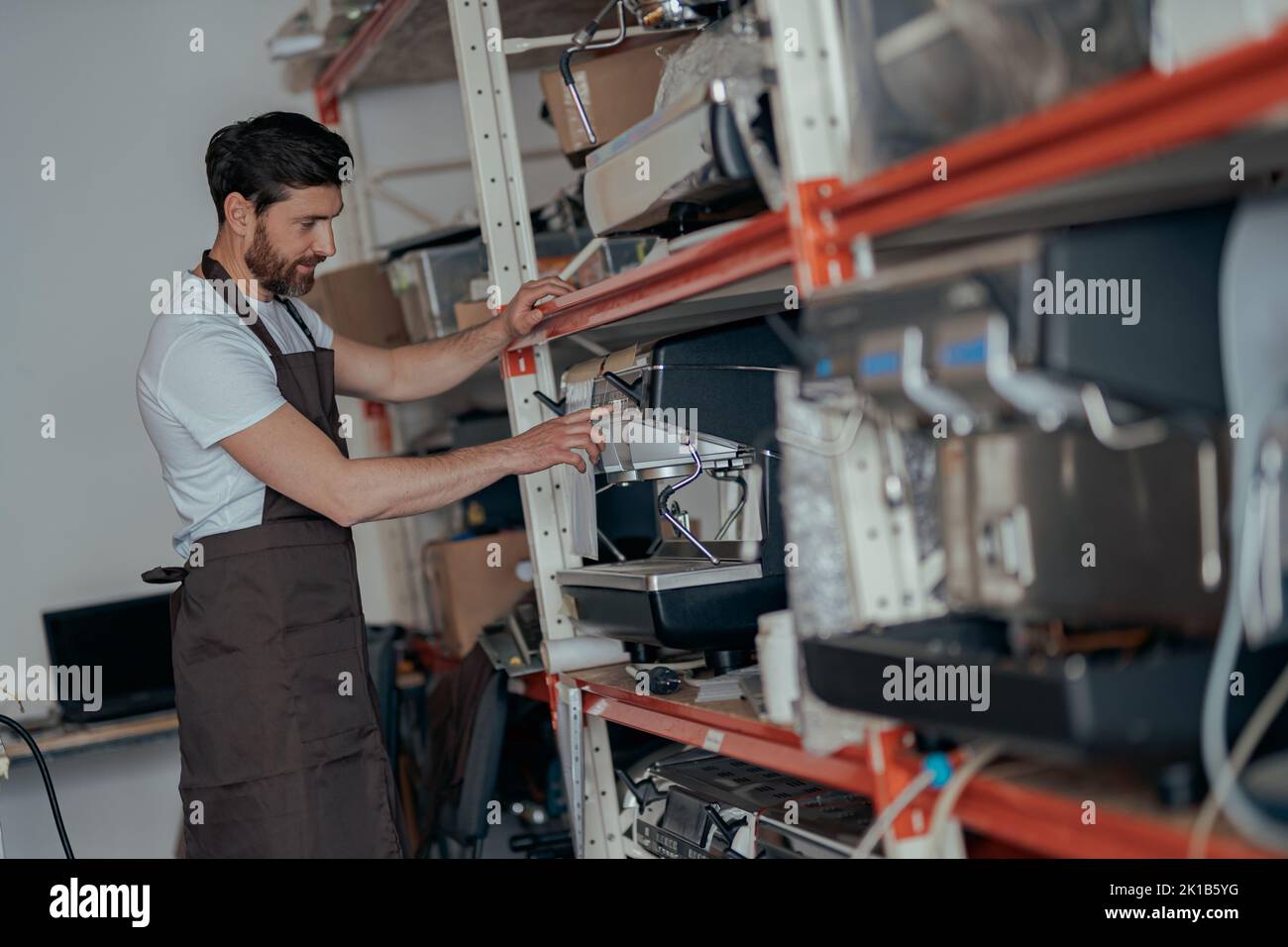 Man worker in uniform inspecting coffee machine in own workshop Stock Photo