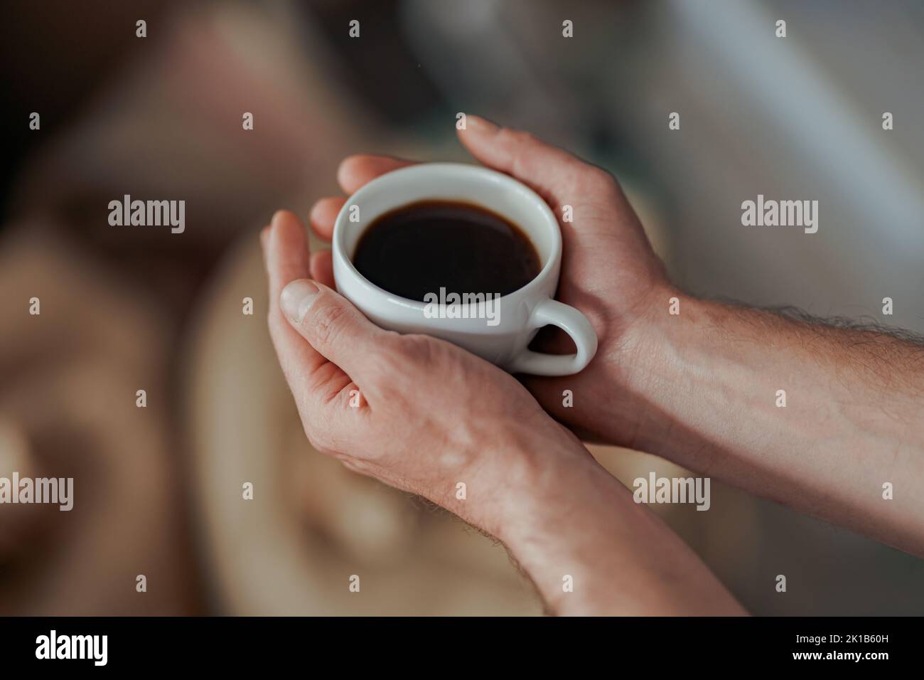 Male hand holding cup of fresh coffee on background of bags with roasted coffee beans Stock Photo