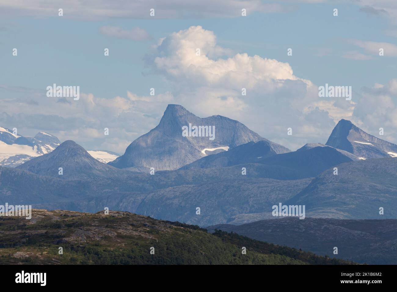 Nature of Norway, wooded landscape with high mountains in the background and green hills in the foreground. Stock Photo